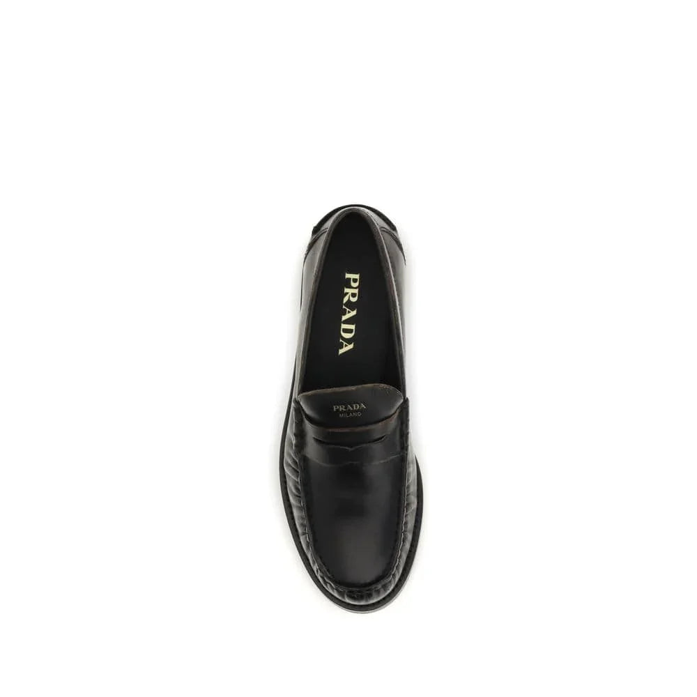 Black leather designer loafer shoe top view, classic slip-on style, minimal white background