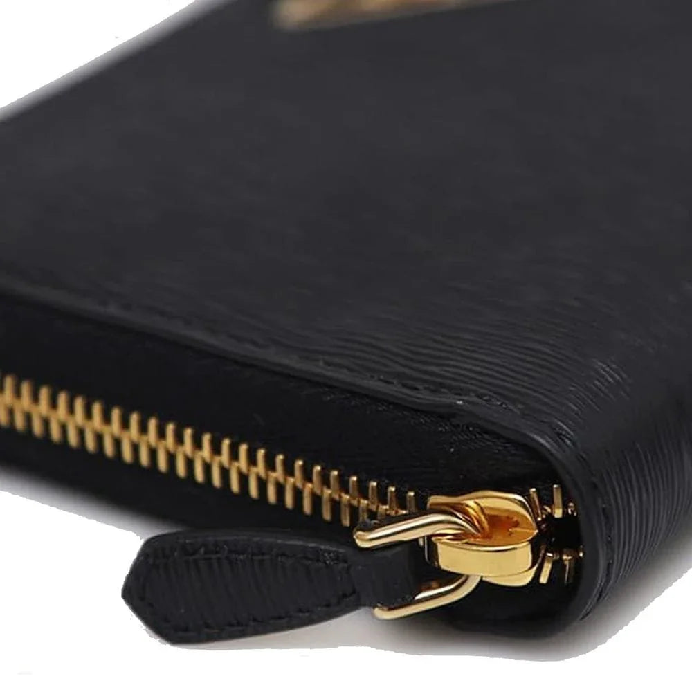 Close-up of black textured leather wallet with gold zipper and pull tab