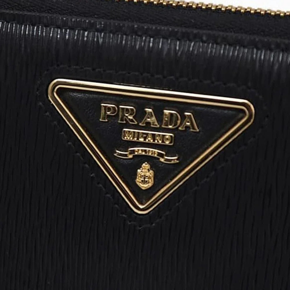 Close-up of a black textured designer bag with a gold triangular logo plaque