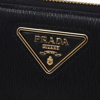 Close-up of a black textured designer bag with a gold triangular logo plaque