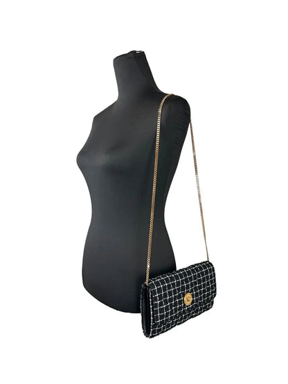 Black and white tweed crossbody bag with gold chain strap on mannequin