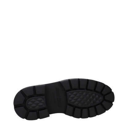 Black chunky rubber sole of a designer boot with textured tread pattern on white background