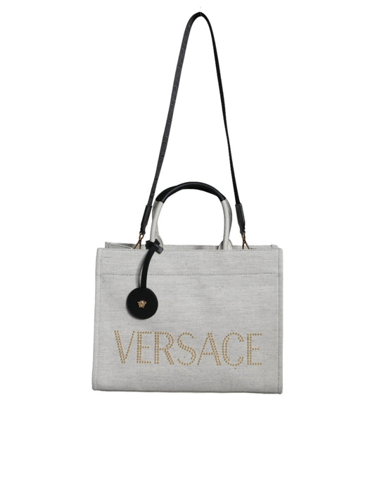 Beige Versace tote bag with gold studded logo, black leather handles, and detachable strap