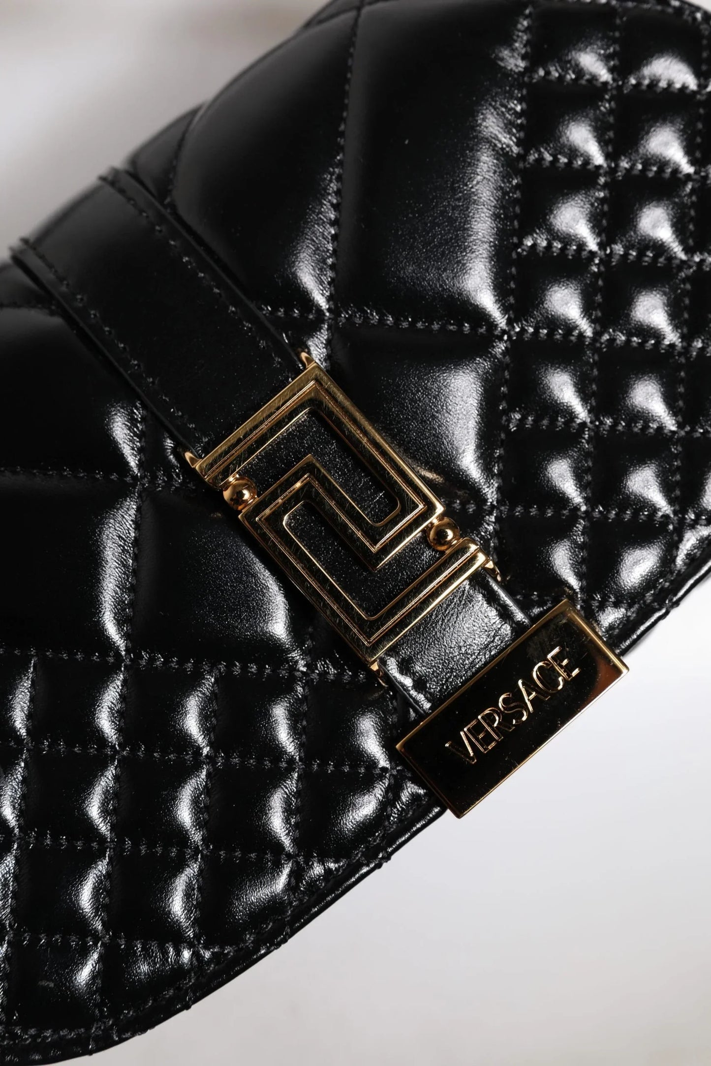 Quilted black leather designer bag with gold Versace logo and geometric clasp detail