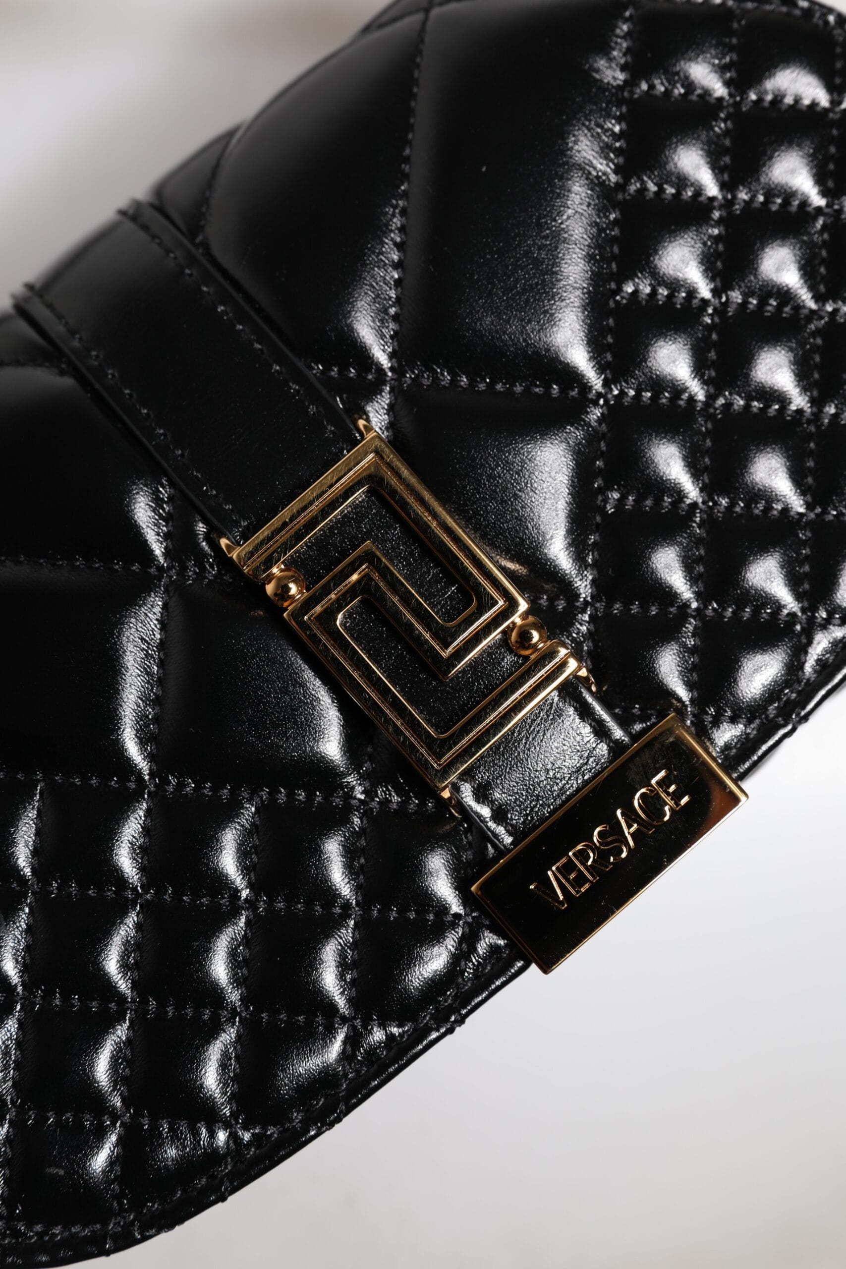 Quilted black leather designer bag with gold Versace logo and geometric clasp detail
