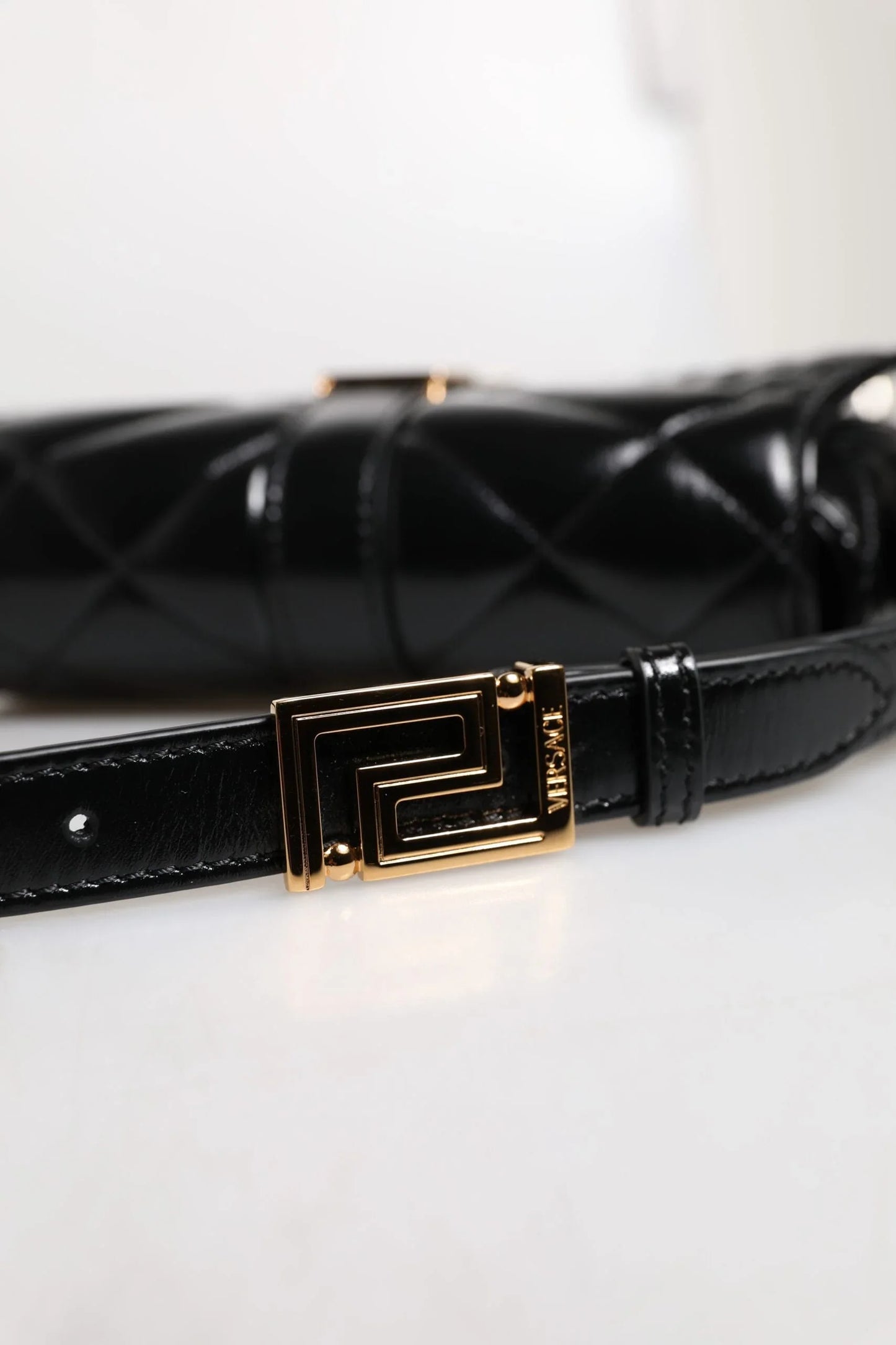 Black quilted designer handbag with gold geometric buckle and premium leather strap