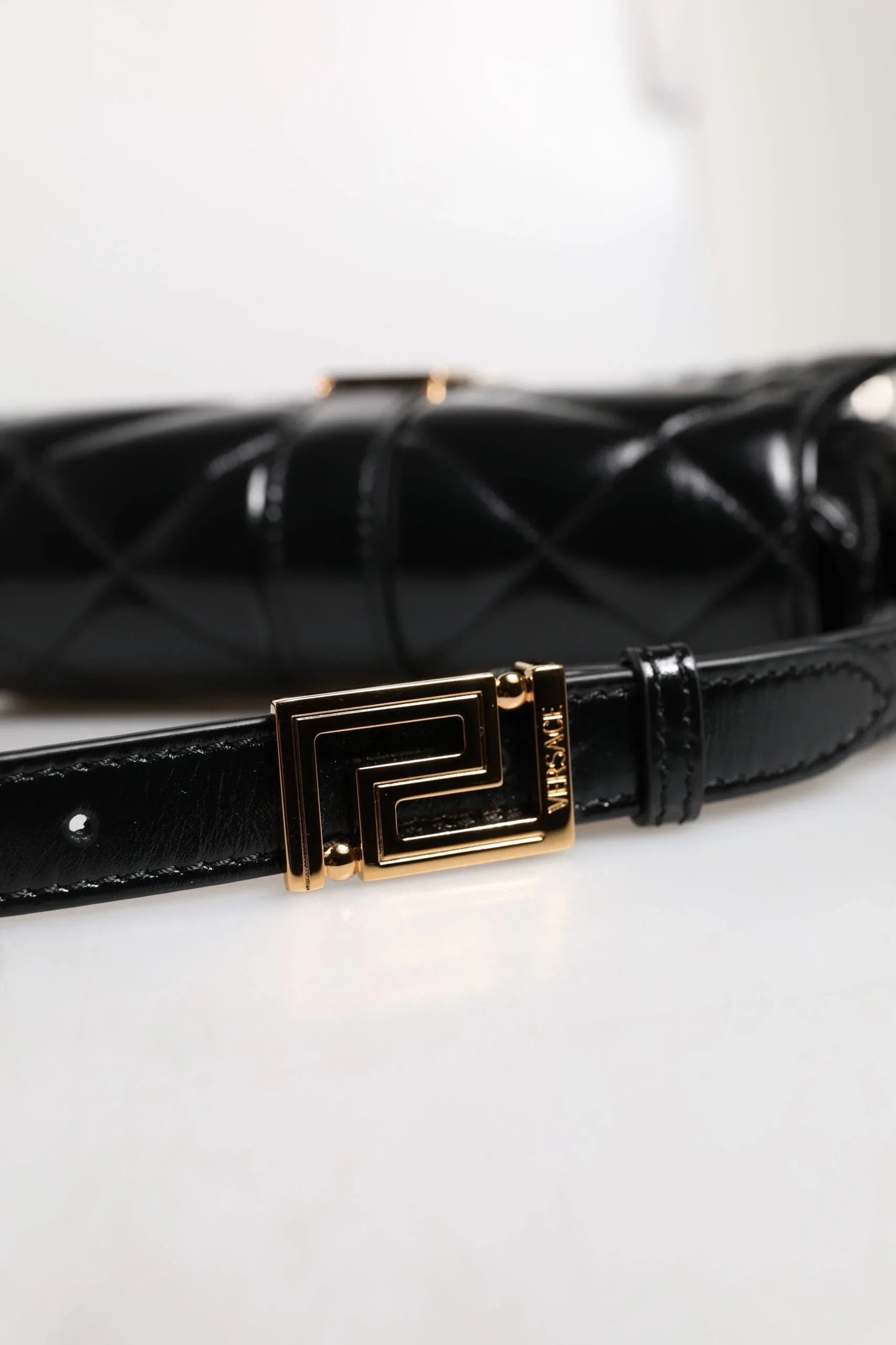 Black quilted designer handbag with gold geometric buckle and premium leather strap