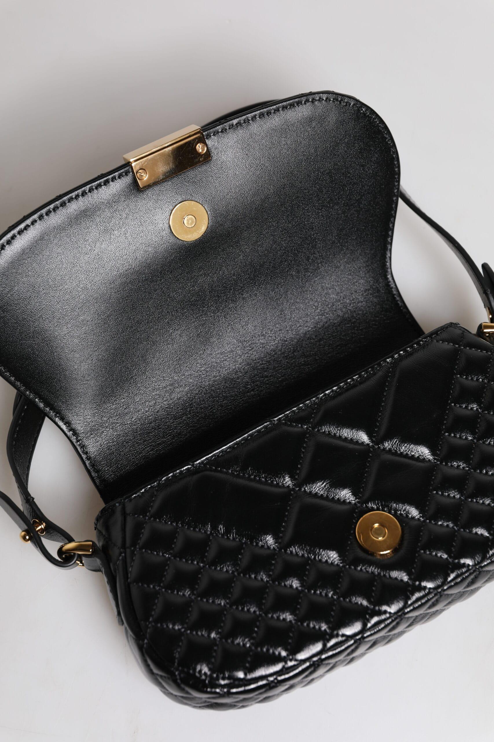 Open black quilted leather shoulder bag with gold magnetic clasp on white background