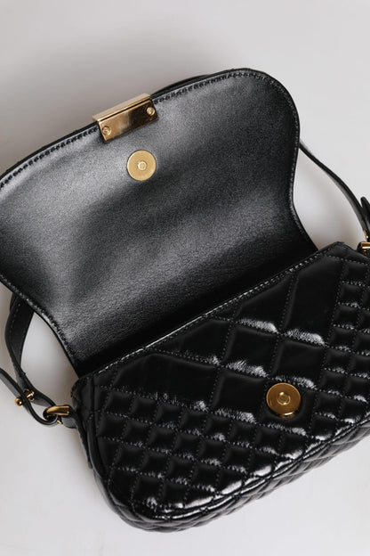 Open black quilted leather shoulder bag with gold magnetic clasp on white background