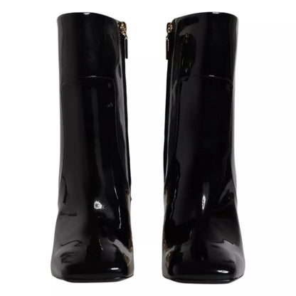 Black patent leather ankle boots with square toes and gold side zippers, front view