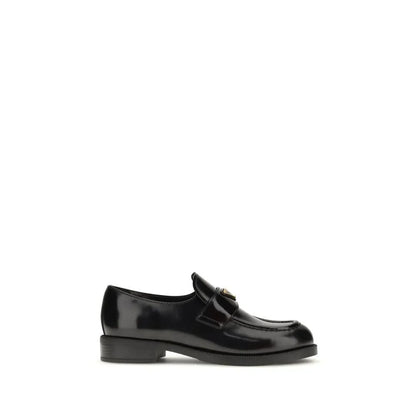 Black leather loafer with low heel and gold hardware on white background