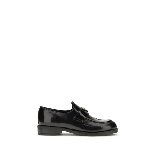 Black leather loafer with low heel and gold hardware on white background
