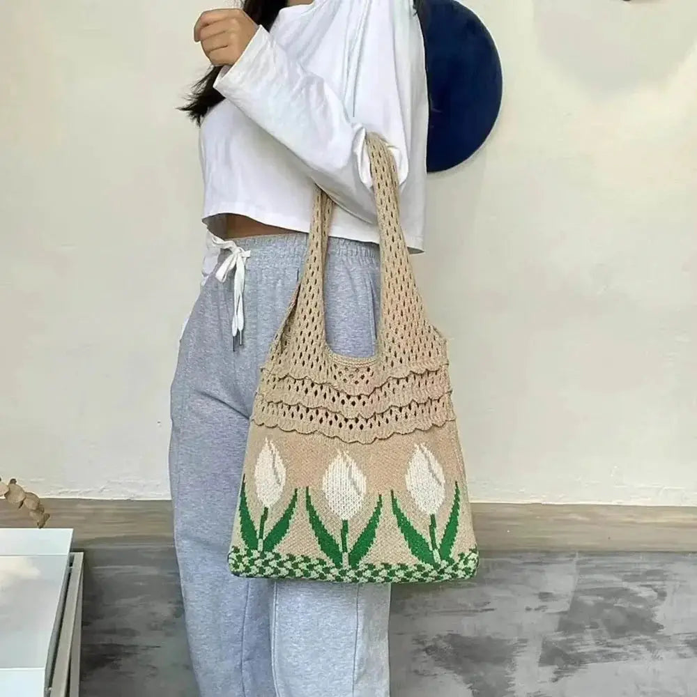 Beige crochet tote bag with white tulip flower pattern, worn by woman in casual outfit