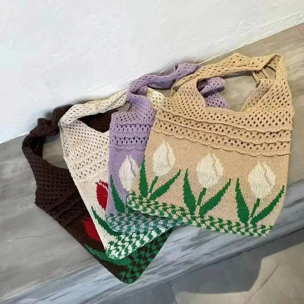 Colorful crochet tote bags with tulip flower patterns, displayed on a stone surface.