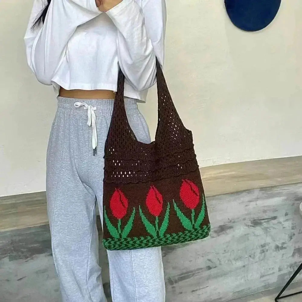 Brown crochet tote bag with red tulip pattern, worn over shoulder, casual outfit