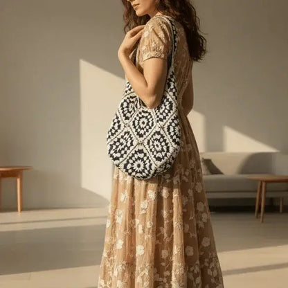 Woman wearing a floral dress with a navy and white hand-woven cotton yarn shoulder bag