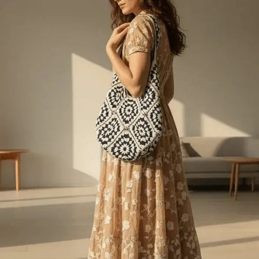 Woman wearing a floral dress with a navy and white hand-woven cotton yarn shoulder bag