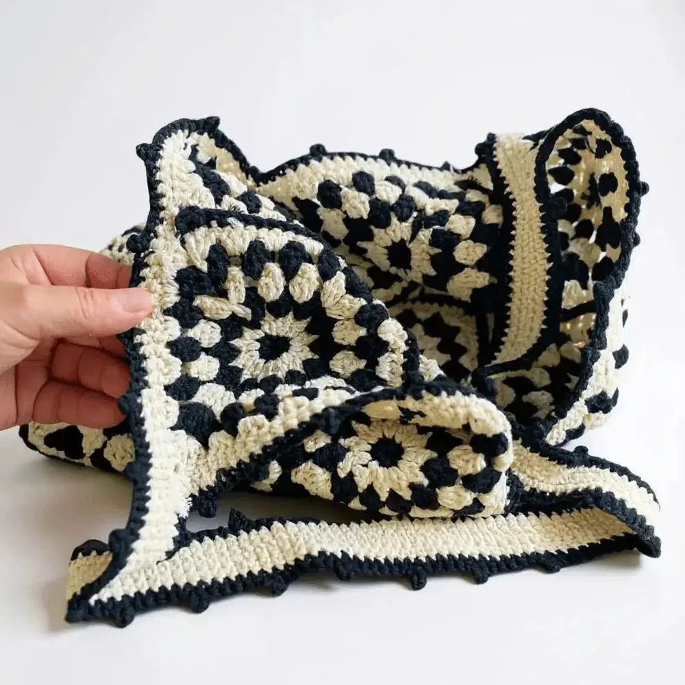 Hand holding black and cream cotton yarn crochet shoulder bag with geometric pattern