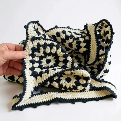 Hand holding black and cream cotton yarn crochet shoulder bag with geometric pattern