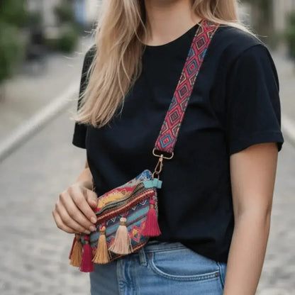 Woman wearing a colorful woven crossbody bag with tassels and a patterned strap