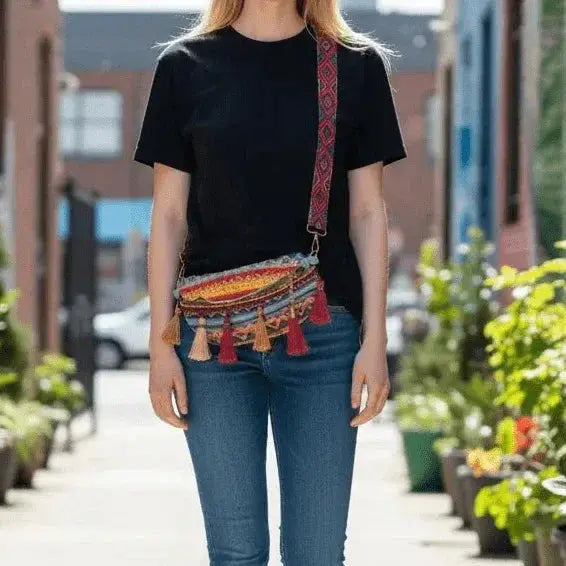 Colorful woven crossbody bag with tassels and patterned strap worn by woman outdoors
