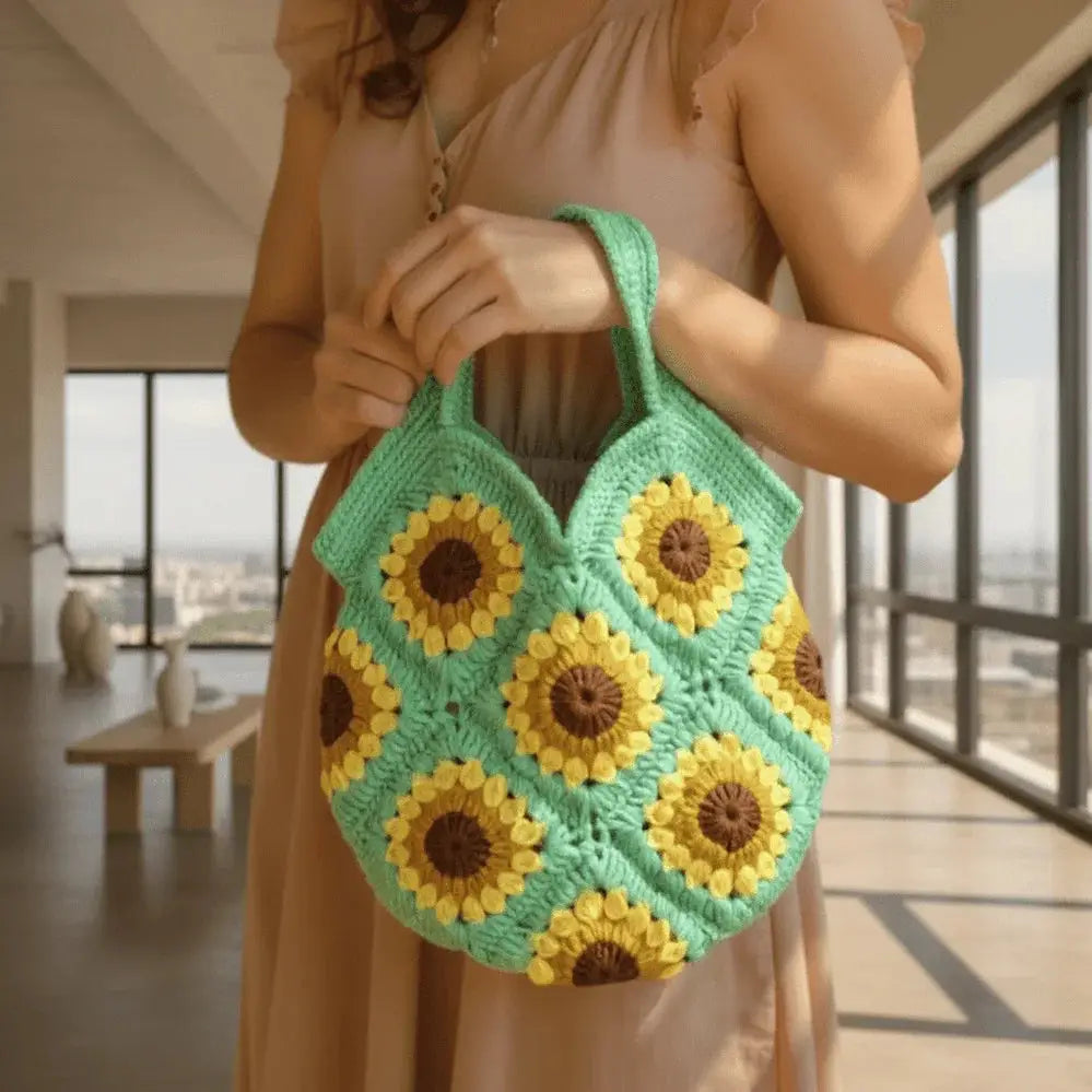 Handmade crochet bag with sunflower pattern and green cotton, held by a woman indoors.