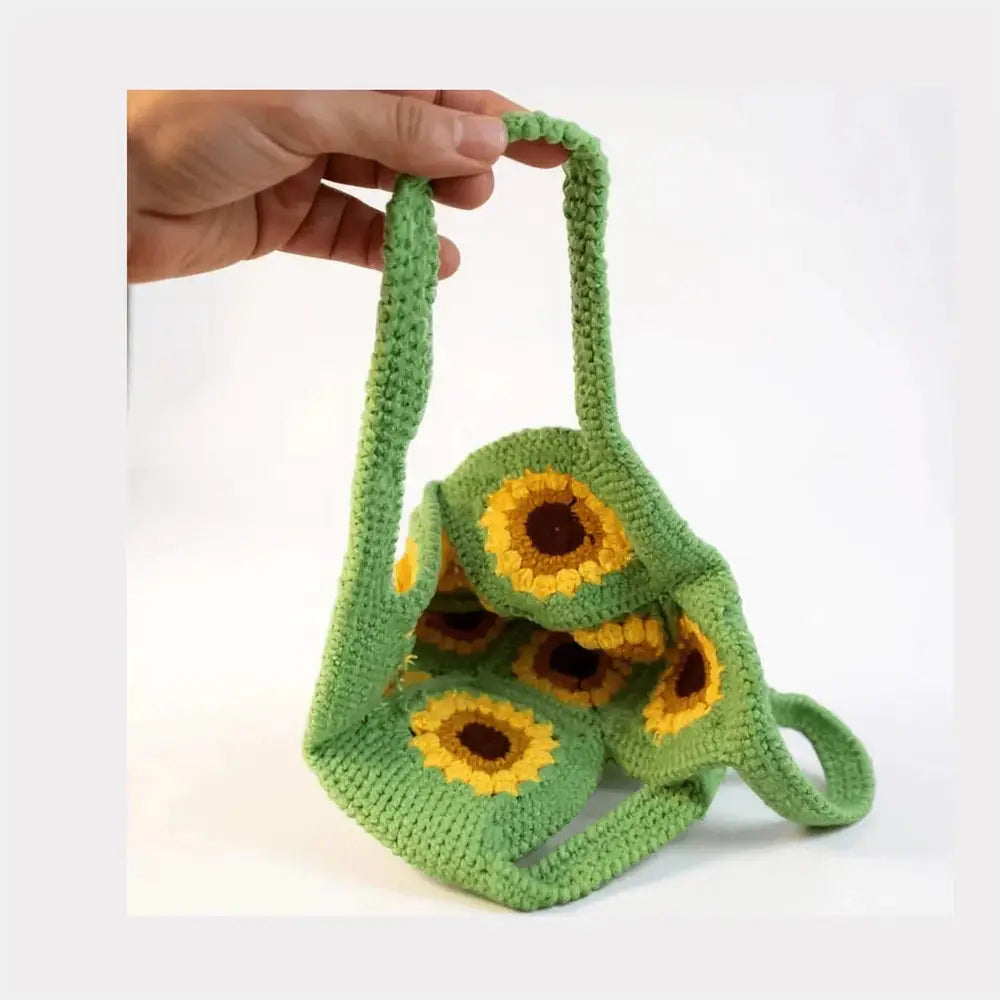 Hand holding a green handmade crochet bag with yellow sunflower patterns, boho cotton handbag