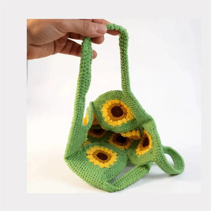 Hand holding a green handmade crochet bag with yellow sunflower patterns, boho cotton handbag