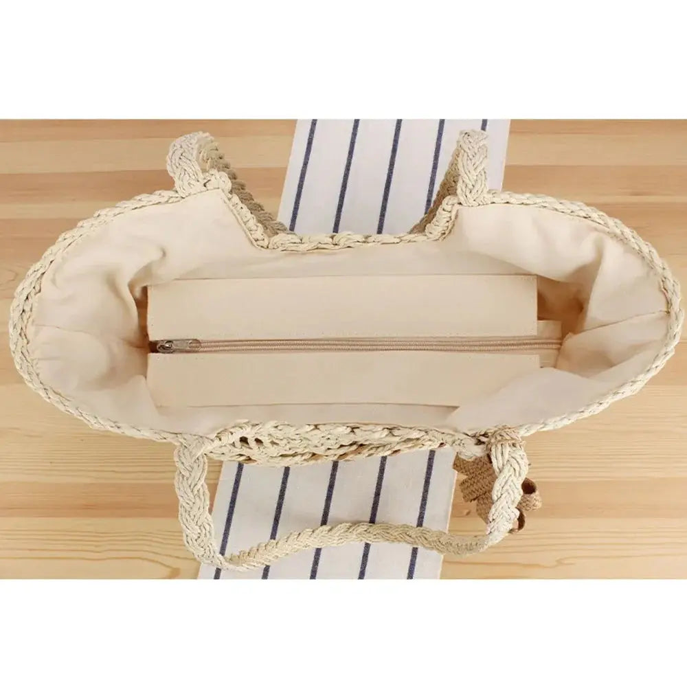Top view of large handmade woven straw beach bag with braided handles and zippered inner pocket