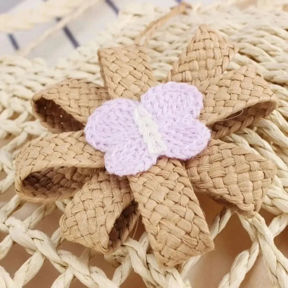 Close-up of handmade woven straw beach bag with braided flower and knit butterfly detail