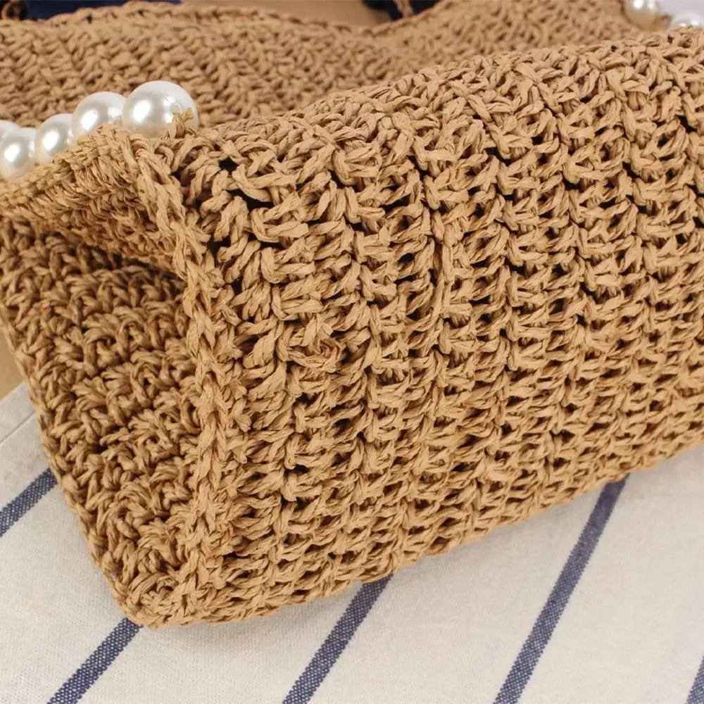 Close-up of woven raffia tote bag with ruffle edge and decorative pearl accents.