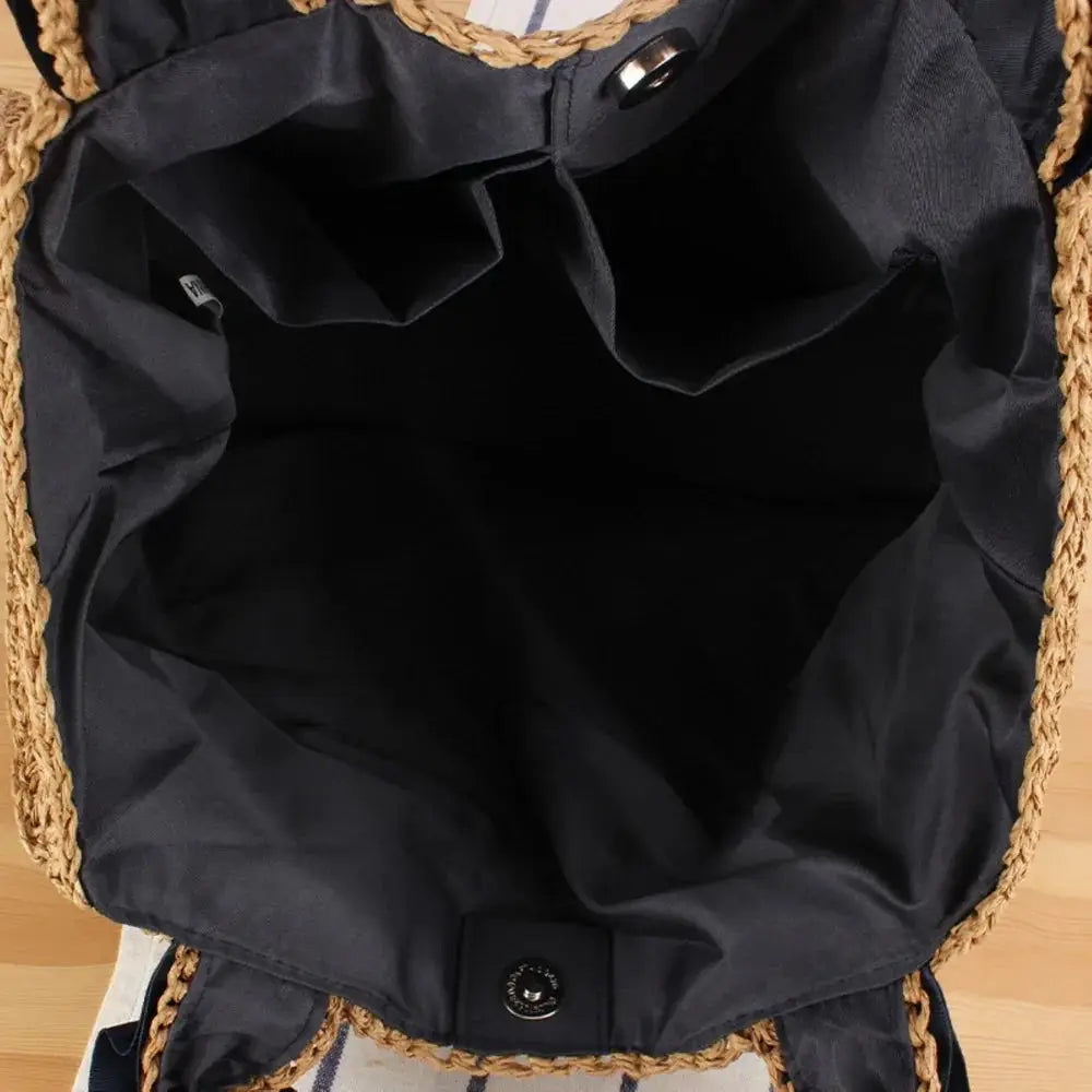 Interior view of woven raffia tote bag with black fabric lining and inner pockets