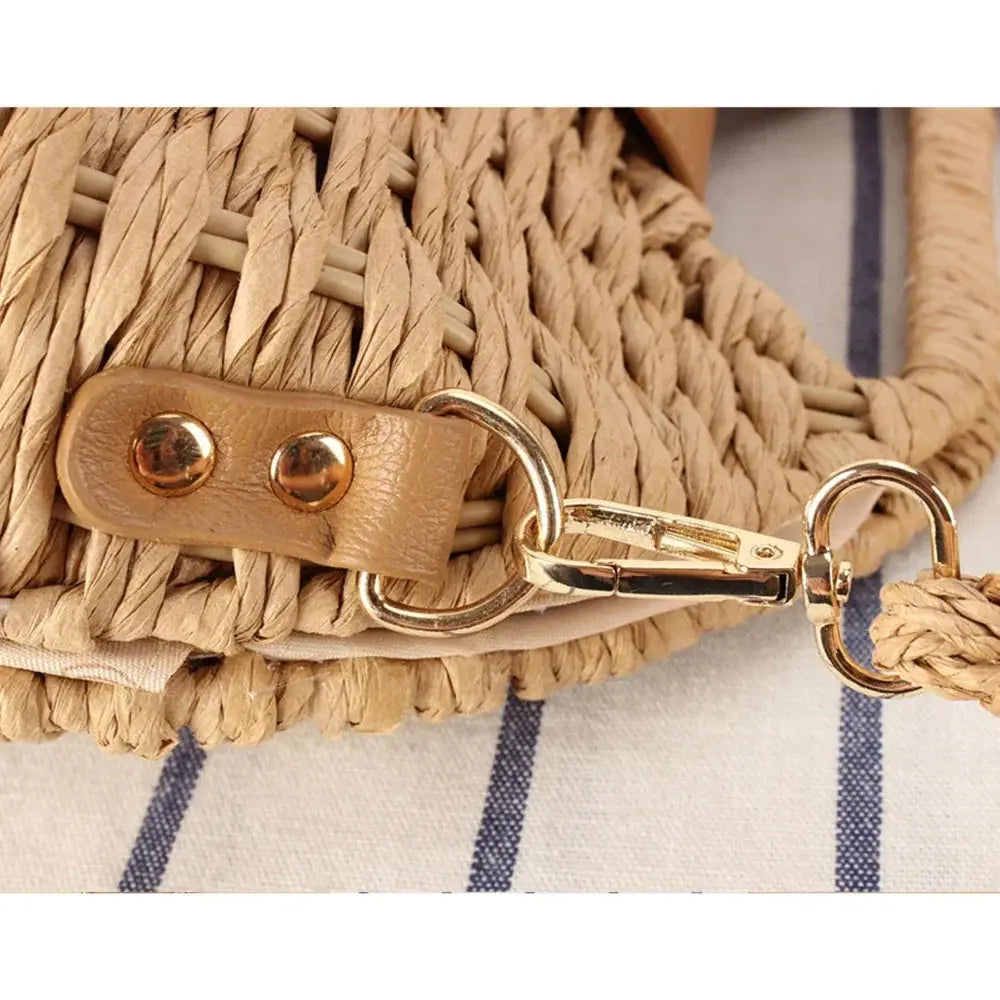 Close-up of woven straw crossbody bag with gold clasp and leather strap detail